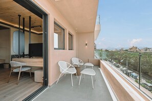 Un balcón con zona de estar, televisión y vistas de la ciudad.