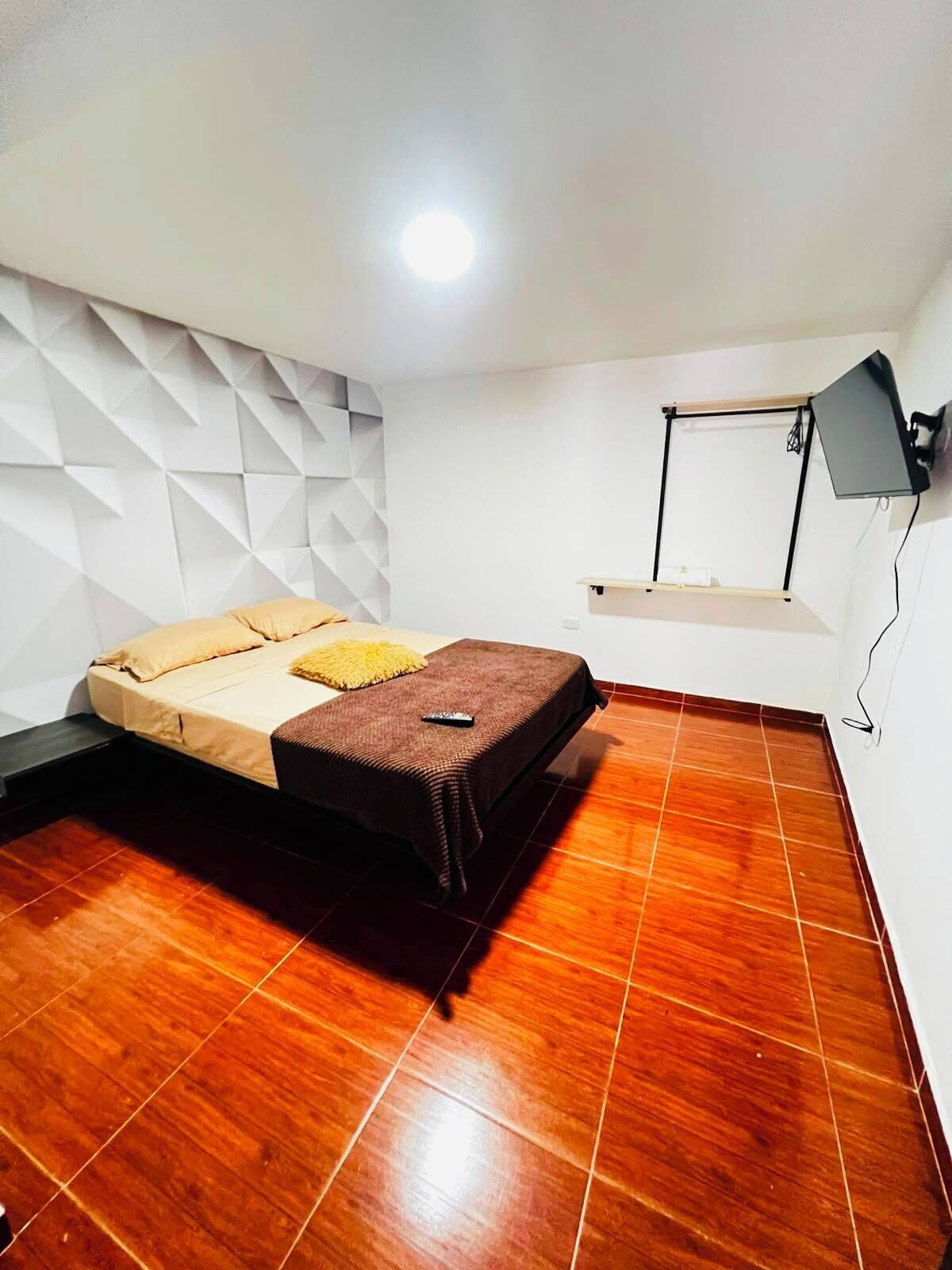 Ein Schlafzimmer mit einem Bett, einem Schreibtisch und einem an der Wand befestigten Fernseher.