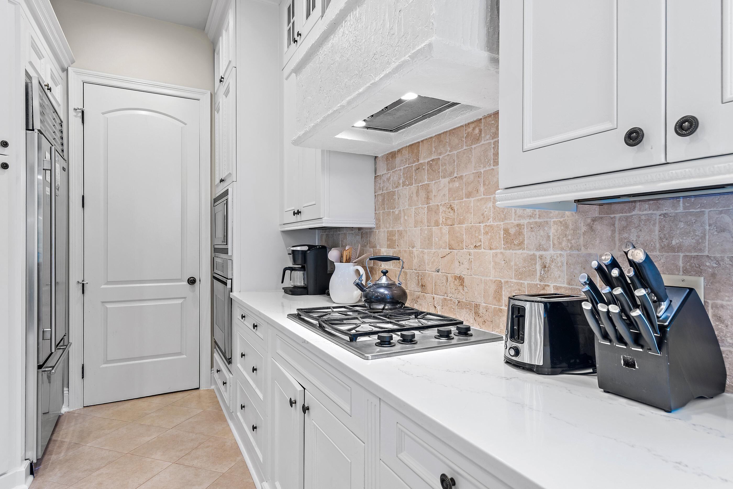 A kitchen with white cabinets, a gas stove, a toaster, and a knife block.