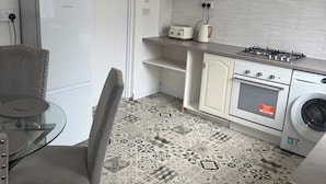 A compact kitchen with a refrigerator, a toaster, a stove, and a washing machine.
