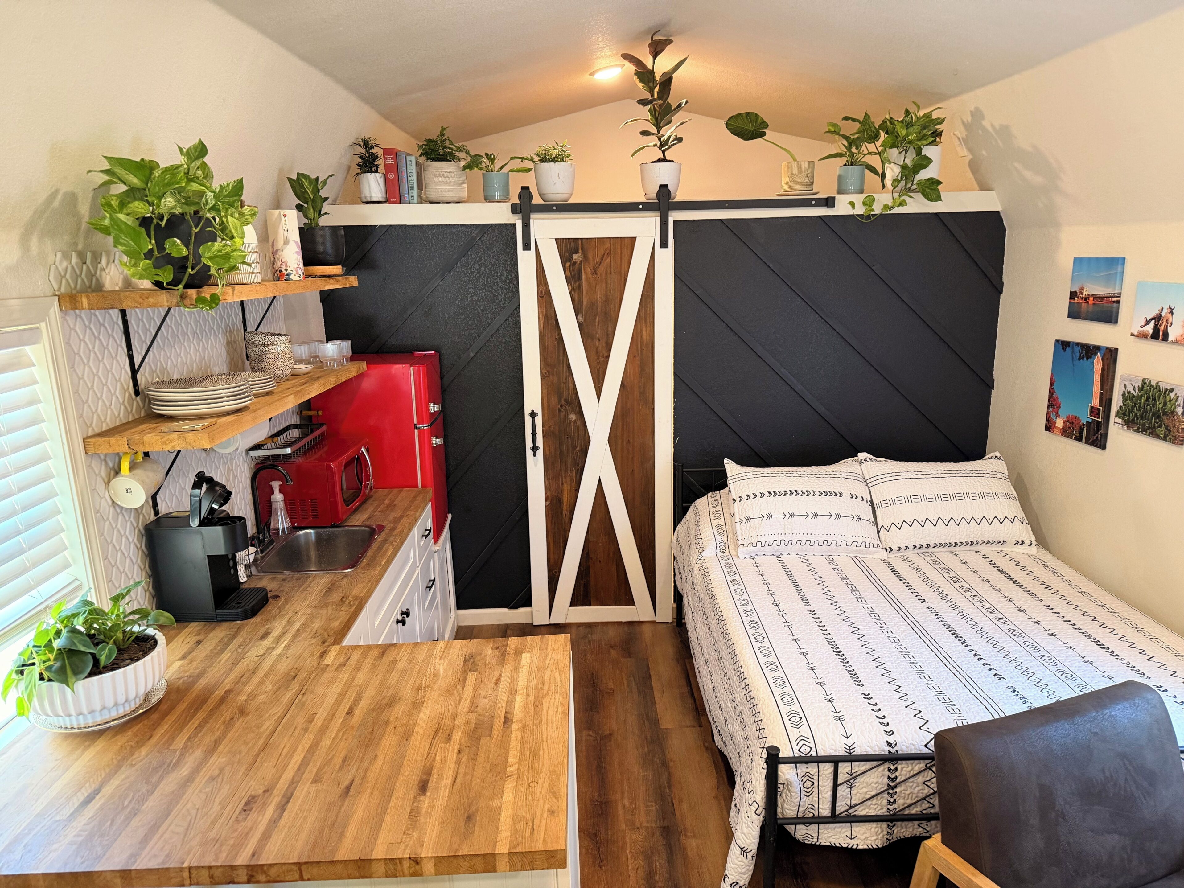 A compact room with a bed, a small kitchenette, and a wooden table.