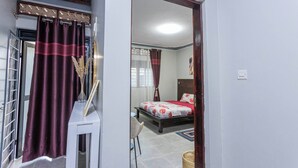 Um quarto com cama, uma cadeira, mesa de cabeceira e janela com cortinas.