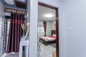 Ein Schlafzimmer mit einem Bett, einem Sessel, einem Nachttisch und einem Fenster mit Vorhängen.