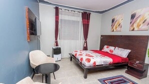 Quarto com cama, poltrona, mesinha, aquecedor e obras de arte na parede.