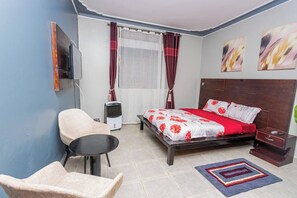 Ein Schlafzimmer mit einem Bett, einem Sessel, einem kleinen Tisch, einem Heizkörper und Bildern an der Wand.