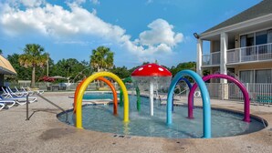A water feature with colorful arches in a pool area, surrounded by a building with a balcony.