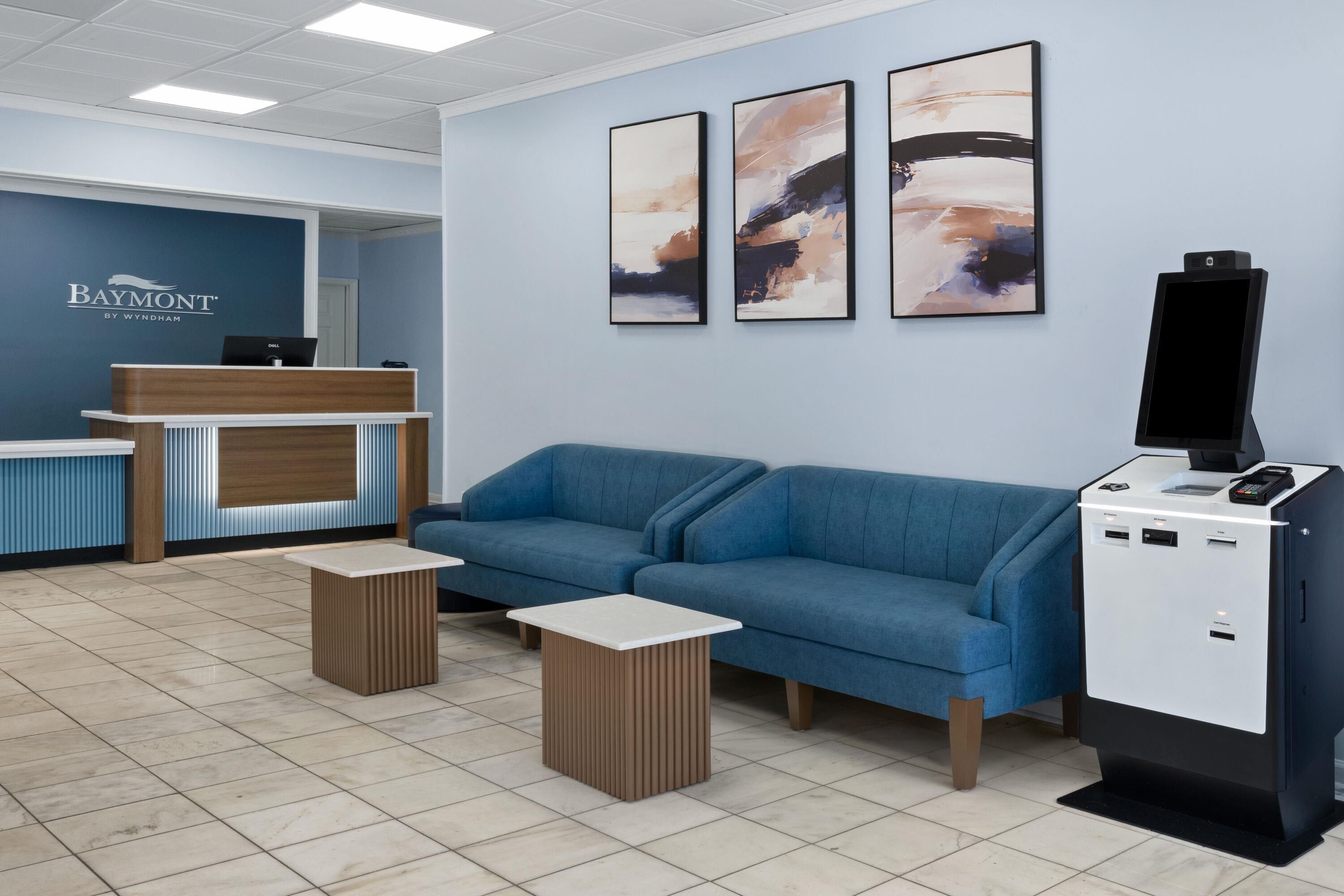 Un espace d’accueil avec un canapé bleu, un comptoir de réception et un téléviseur fixé au mur.
