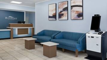 A reception area with a blue sofa, a reception desk, and a mounted TV.