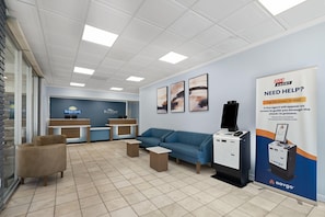 A reception area with a blue sofa, a desk, and a computer. There are framed artworks on the wall and a banner advertising live agent assistance.