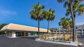 A hotel with a flat-roofed building, a covered outdoor area, and a landscaped garden with a water feature.