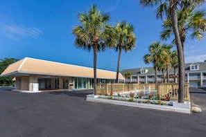 A hotel with a flat-roofed building, a covered outdoor area, and a landscaped garden with a water feature. - Days Inn By Wyndham Pawleys Island (Pawleys Island)