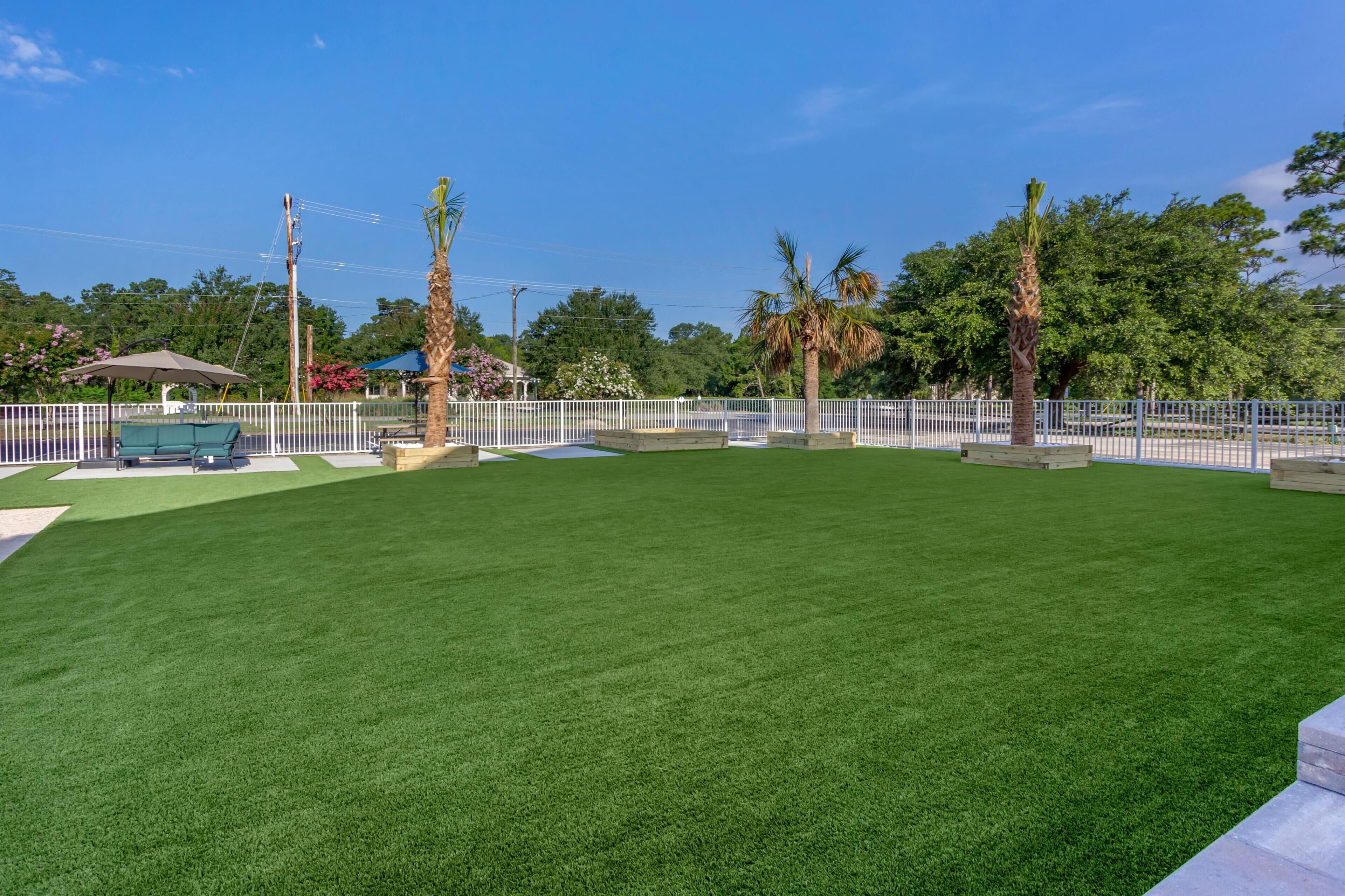 A well-maintained grassy area with a white fence, a bench, and a gazebo.
