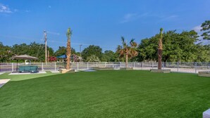 A well-maintained grassy area with a white fence, a bench, and a gazebo.