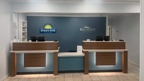 A reception desk with two computer stations, a blue wall with logos of Days Inn and Baymont, and a tiled floor.