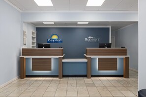 A reception area with two reception desks, a blue wall with logos, and a tiled floor. - Days Inn By Wyndham Pawleys Island (Pawleys Island)
