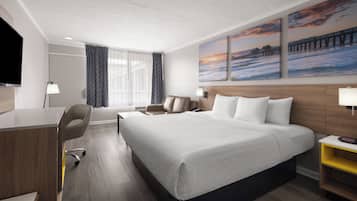 Habitación de hotel con cama, escritorio, silla y una obra de arte en la pared.