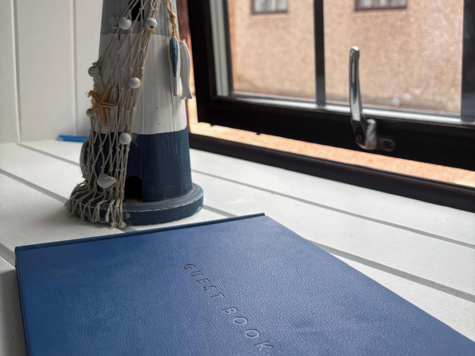 A blue book titled 'GUEST BOOK' on a windowsill.