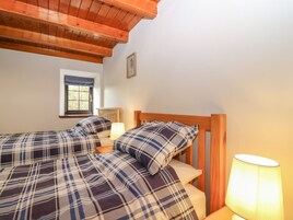 Un dormitorio con dos camas, una ventana y una lámpara.