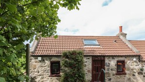 A stone house with a tiled roof, a small window, and a door. - Viola Cottage (Fraserburgh)