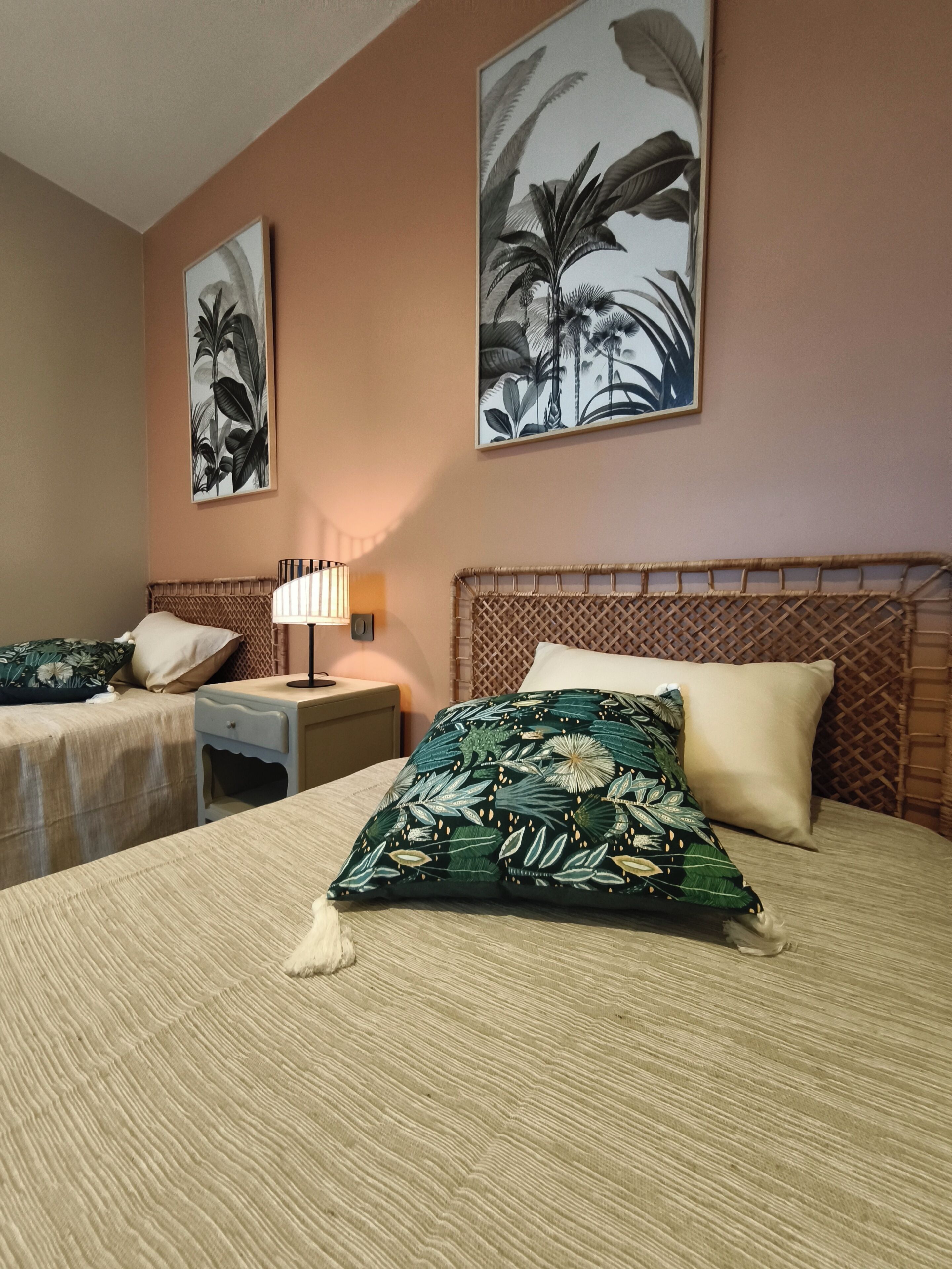 Una habitación de hotel con dos camas, una mesita de noche con lámpara y obras de arte en las paredes.