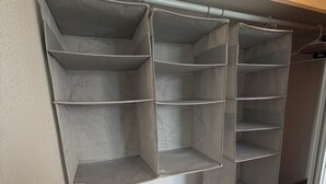 Ein Schrank mit mehreren Regalen und einer Kleiderstange.