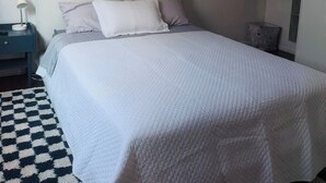 Ein Schlafzimmer mit einem Bett, einem Nachttisch, einer Lampe, einem Deckenventilator und einem gemusterten Teppich.