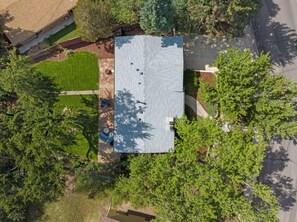 An aerial view of a residential property with a flat roof, a well-maintained lawn, and surrounding trees. - THE SUNSET HOUSE 3-Bedroom, 2-Bath House in Central Colorado Springs. (Colorado Springs)