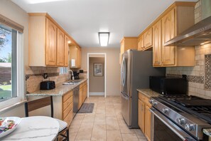 A modern kitchen with wooden cabinets, a stainless steel refrigerator, a stove, and a microwave. - THE SUNSET HOUSE 3-Bedroom, 2-Bath House in Central Colorado Springs. (Colorado Springs)