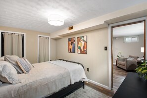 A bedroom with a bed, curtains, a painting, and a view into another room. - THE SUNSET HOUSE 3-Bedroom, 2-Bath House in Central Colorado Springs. (Colorado Springs)