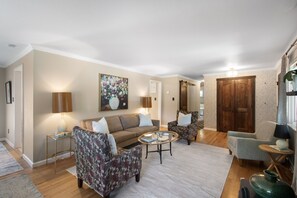 Ein Wohnzimmer mit einer Couch, zwei Sesseln, einem Couchtisch und einem Bild an der Wand.