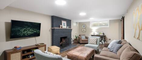 A living room with a flat-screen TV, a fireplace, and a sofa.