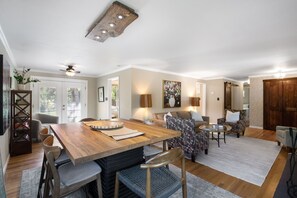 A spacious living area with a wooden dining table, comfortable seating, and a large painting on the wall. - THE SUNSET HOUSE 3-Bedroom, 2-Bath House in Central Colorado Springs. (Colorado Springs)