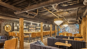 Un espace bar avec des tabourets de bar en bois, un comptoir et une fresque murale représentant l’année 1865.