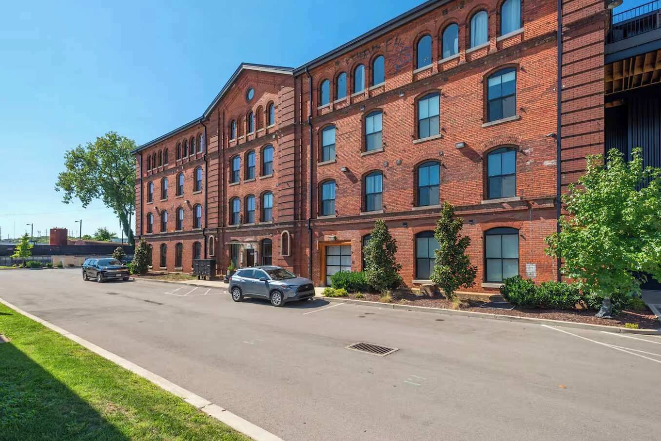 A multi-story brick building with a parking lot in front.