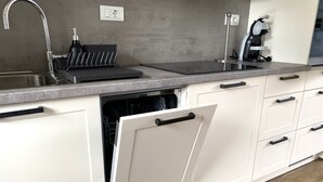 Eine Küche mit Spüle aus Edelstahl, Geschirrspüler und Kaffeemaschine.