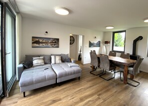 A modern living room with a sofa, dining table, chairs, and a fireplace. - BLED LAKE HOUSE - Apartment Castle (Bled)