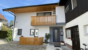 Ein zweistöckiges Gebäude mit Balkon, einer Tür mit Hausnummer und einem Fahrrad vor der Tür.