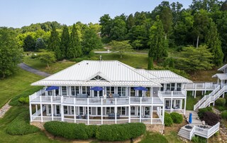 A large, multi-story building with a white exterior, multiple balconies, and a covered outdoor area with blue umbrellas.
