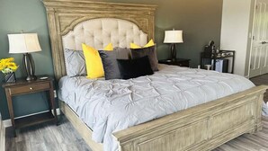 Un dormitorio con una cama grande, dos mesitas de noche y una mesita auxiliar.