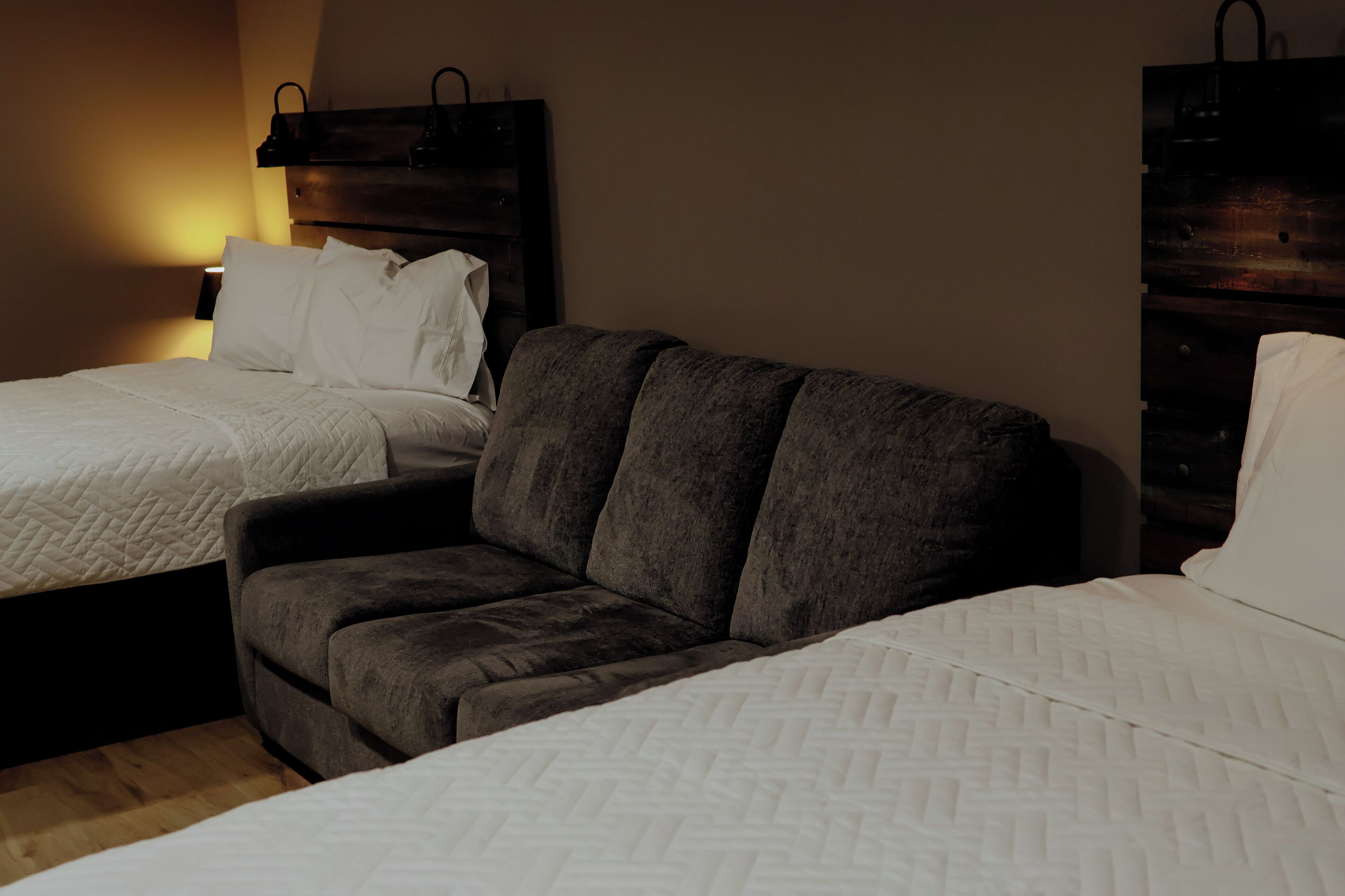 Ein Hotelzimmer mit zwei Betten, einer Couch und einem Nachttisch mit Lampe.