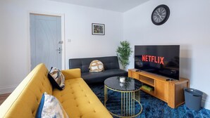 Una sala de estar con un sofá, una mesa de centro, un televisor y una puerta.