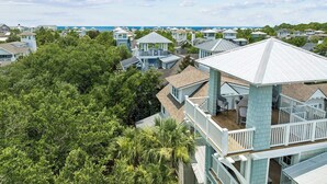 A coastal residential area with multiple houses, some with elevated structures and balconies, surrounded by lush greenery. - Gulf Views, Private Pool and Golf Cart (Watersound)