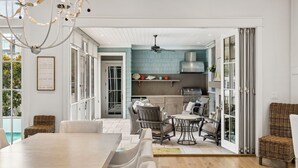 A modern kitchen with a blue backsplash, open shelving, and a dining area with wicker furniture. - Gulf Views, Private Pool and Golf Cart (Watersound)