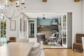 A modern kitchen with a blue backsplash, open shelving, and a dining area with wicker furniture. - Gulf Views, Private Pool and Golf Cart (Watersound)