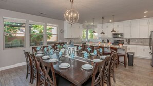 A spacious kitchen with white cabinets, a large island, and a dining area set for six.