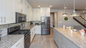 A modern kitchen with stainless steel appliances, granite countertops, and pendant lighting.
