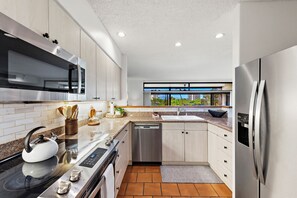 Eine moderne Küche mit Edelstahlgeräten, einem großen Fenster und Blick auf die Stadt.