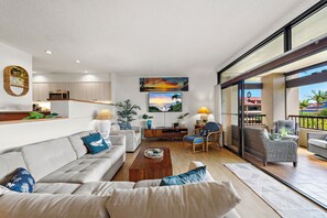 A modern living room with a sofa, coffee table, and a dining area with chairs. - New Family Retreat Near Beaches & Whalers Village (Lahaina)