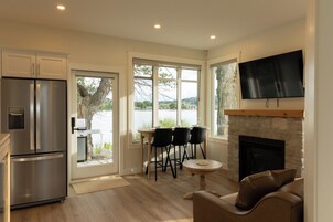 Una cocina moderna con refrigerador integrado, un comedor con mesa y sillas, una chimenea y un televisor montado arriba.