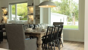 Comedor con una mesa de madera dispuesta para seis personas, rodeada de sillas negras, bajo una lámpara colgante grande.